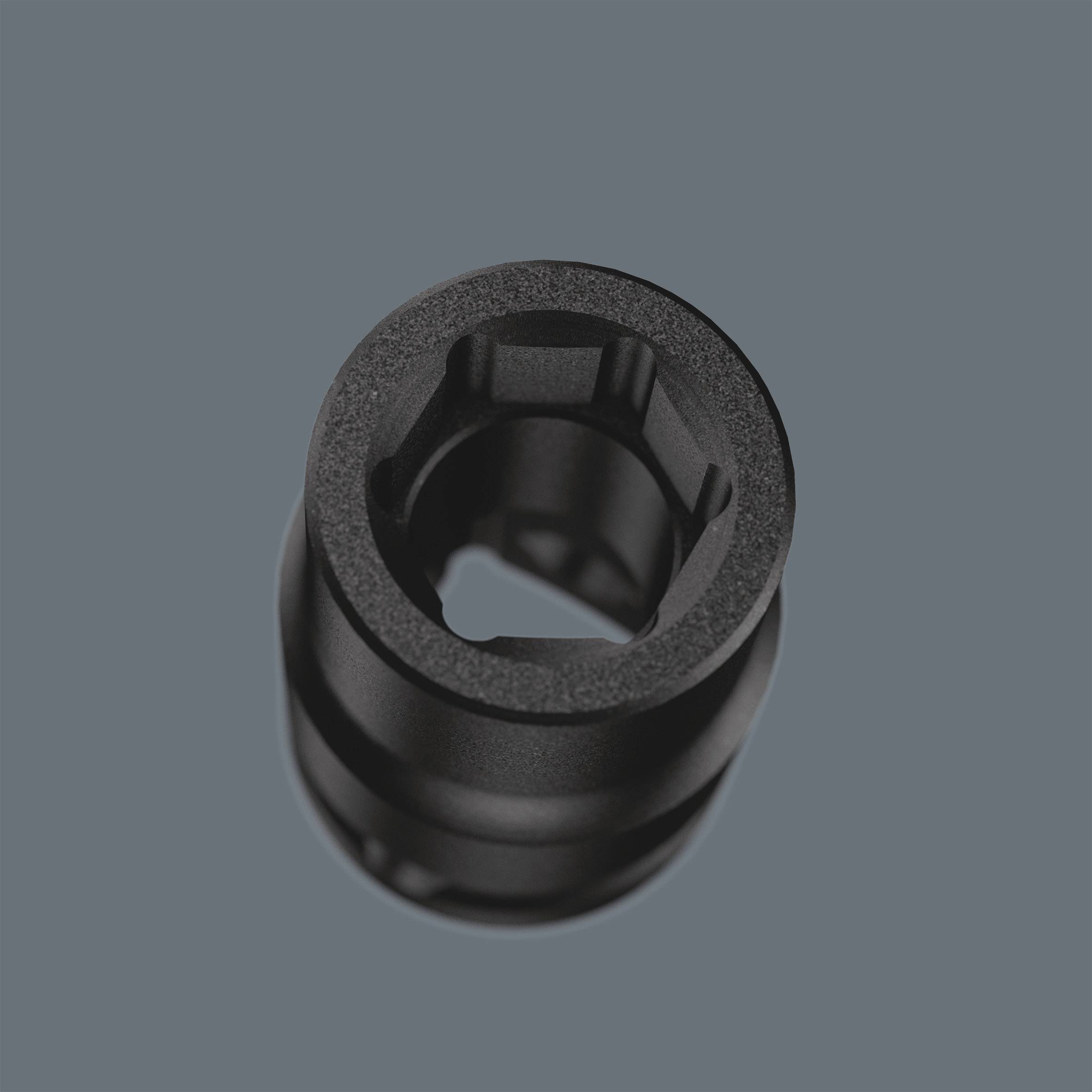 Černý válcovitý objekt před šedým pozadím. Uprostřed má otvor a působí mechanicky.