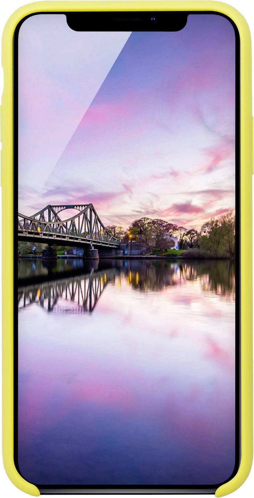 iPhone se žlutým pouzdrem zobrazuje obrázek řeky při západu slunce, s mostem a stromy v pozadí, odrážející se ve vodě.