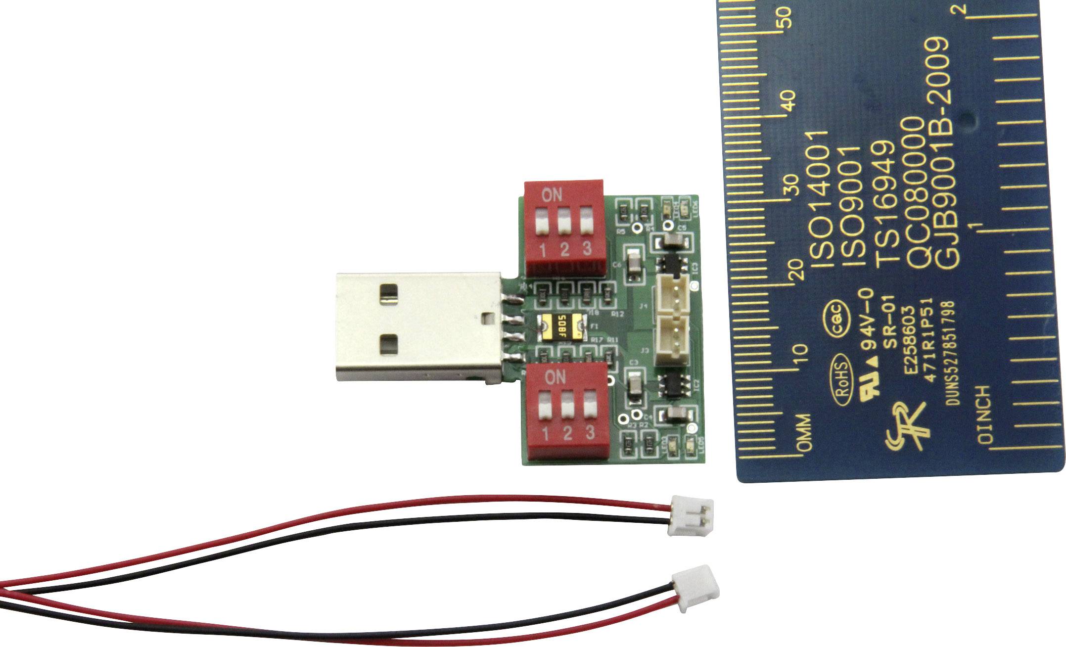 USB modul s přepínači, vedle měřicí stupnice pro srovnání velikosti. Dva samostatné kabely s konektory dole.