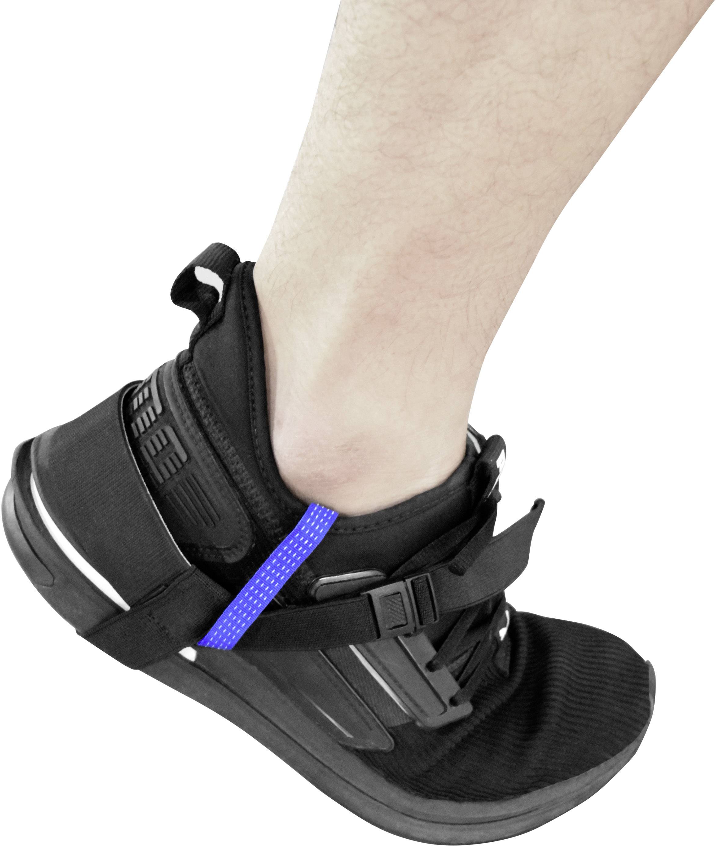 Jedna noha v černé tenisce; bota má suchý zip a modrý elastický pásek kolem paty.