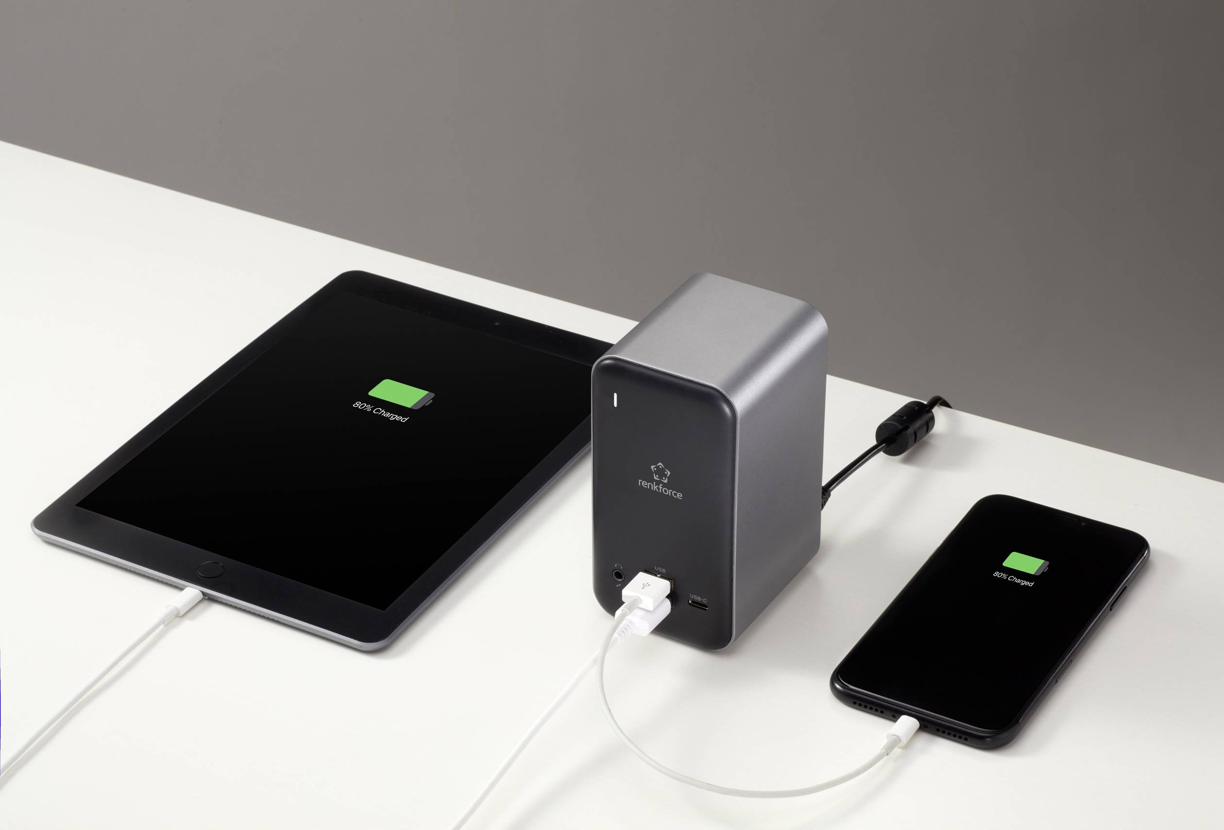 Tablet a smartphone na stole, oba s obrazovkou nabíjení a připojeni k powerbanance.