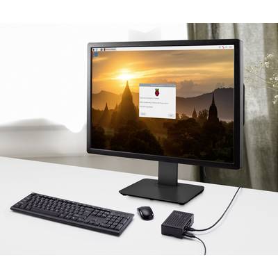 Počítačový monitor s krajinou a logem operačního systému Raspberry Pi, klávesnice, myš a zařízení Raspberry Pi na bílém stole.
