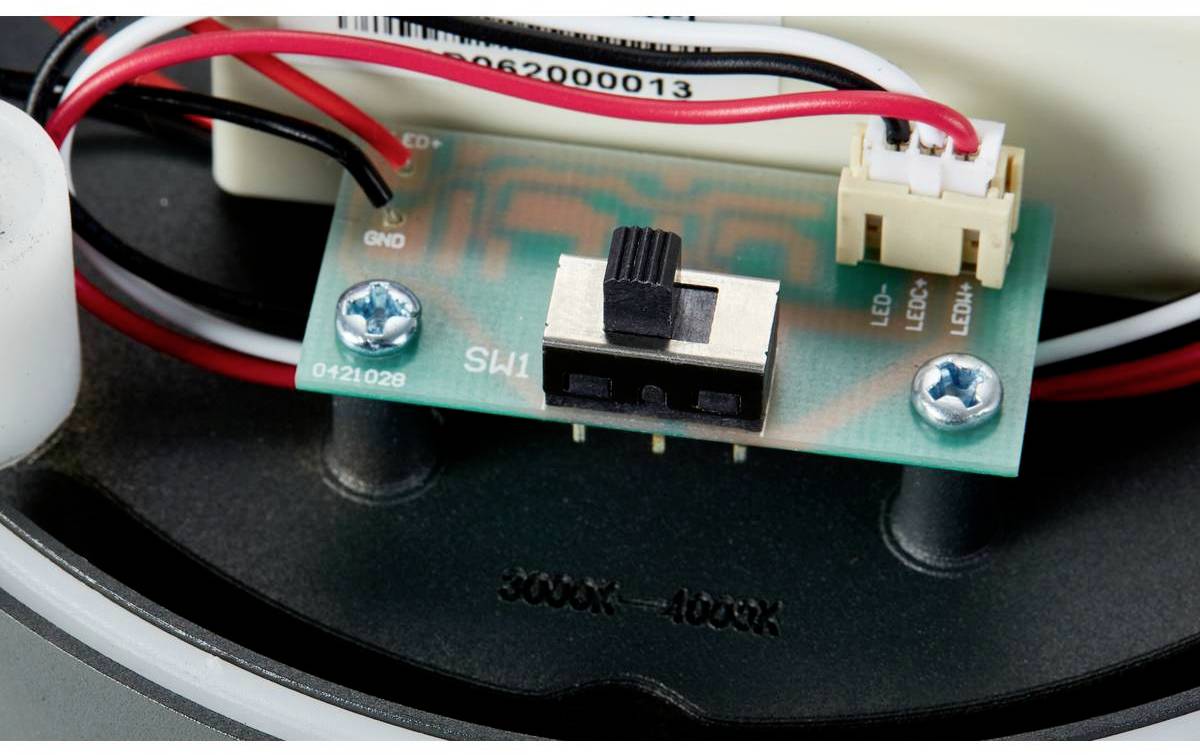 Elektronický spínač na zelené desce plošných spojů s několika propojenými červenými a černými vodiči, upevněný dvěma šrouby.