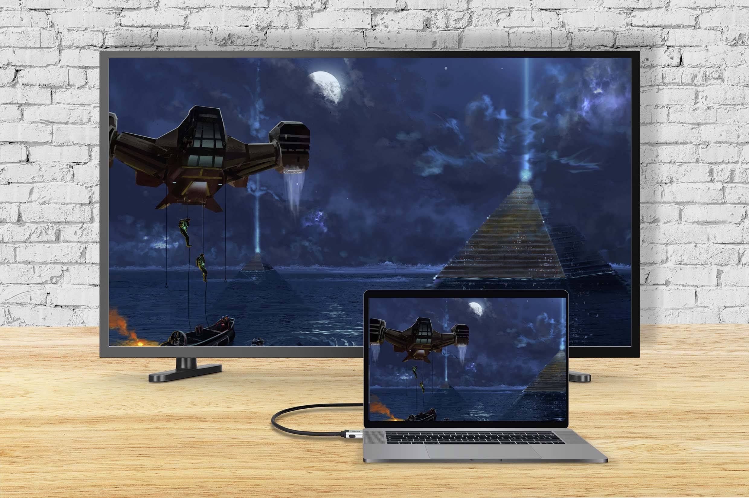 Laptop je pomocí kabelu připojen k velkému televizoru a zobrazuje stejný obraz: futuristickou scénu s pyramidami a vesmírnou lodí.
