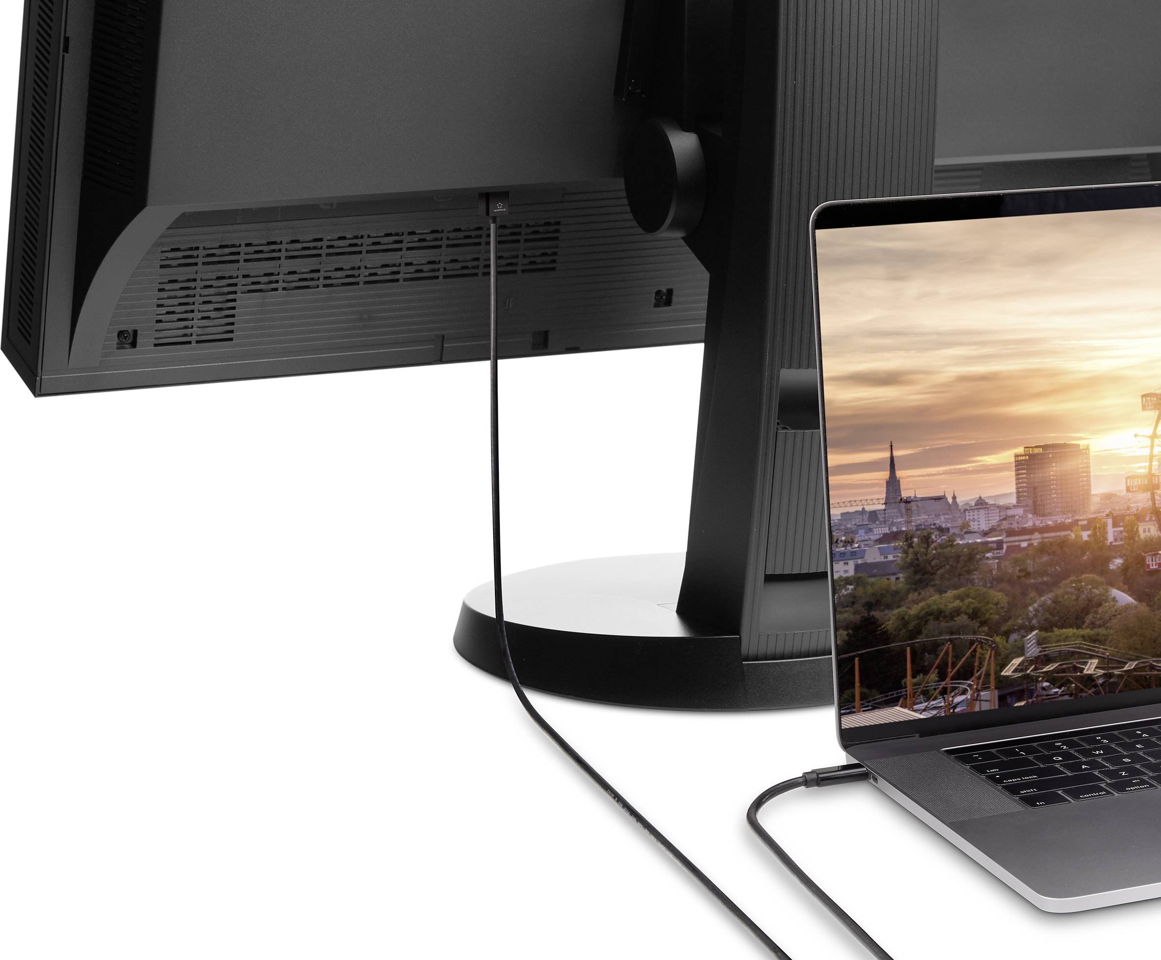 Laptop je připojen k velkému monitoru. Na displeji laptopu je vidět pohled na město s moderní panoramatem mrakodrapů.