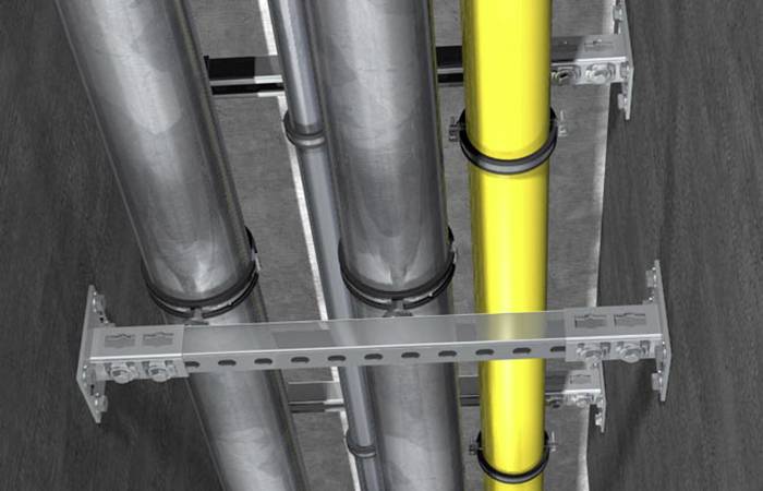 Několik trubek v tunelu. Jedna trubka je žlutá a zvýrazněná. Trubky jsou upevněny na kovovых držácích a vedou souběžně.