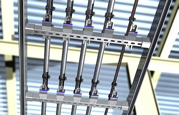 Montáž trubek na lešení, které jsou svisle orientované a upevněné kovovými svorkami. Pozadí je rozmazané.