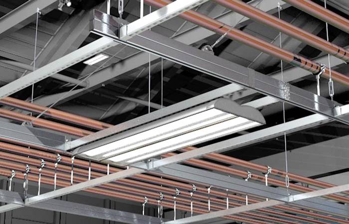 Průmyslová hala se stropem s viditelnými vzduchotechnickými kanály a obdélníkovým stropním světelným tělesem uprostřed.