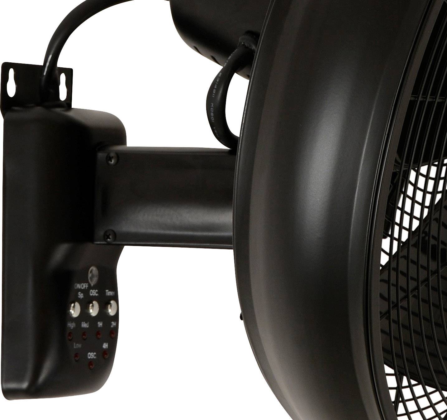 Detailní záběr černého nástěnného ventilátoru s ovládacími prvky u základny, který ukazoval větrákové listy přes ochranný kryt.