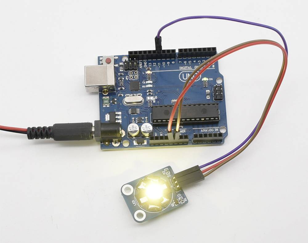 Deska plošných spojů s několika připojenými kabely, která rozsvěcuje LED. Elektronický projekt s mikrokontrolerem Arduino.