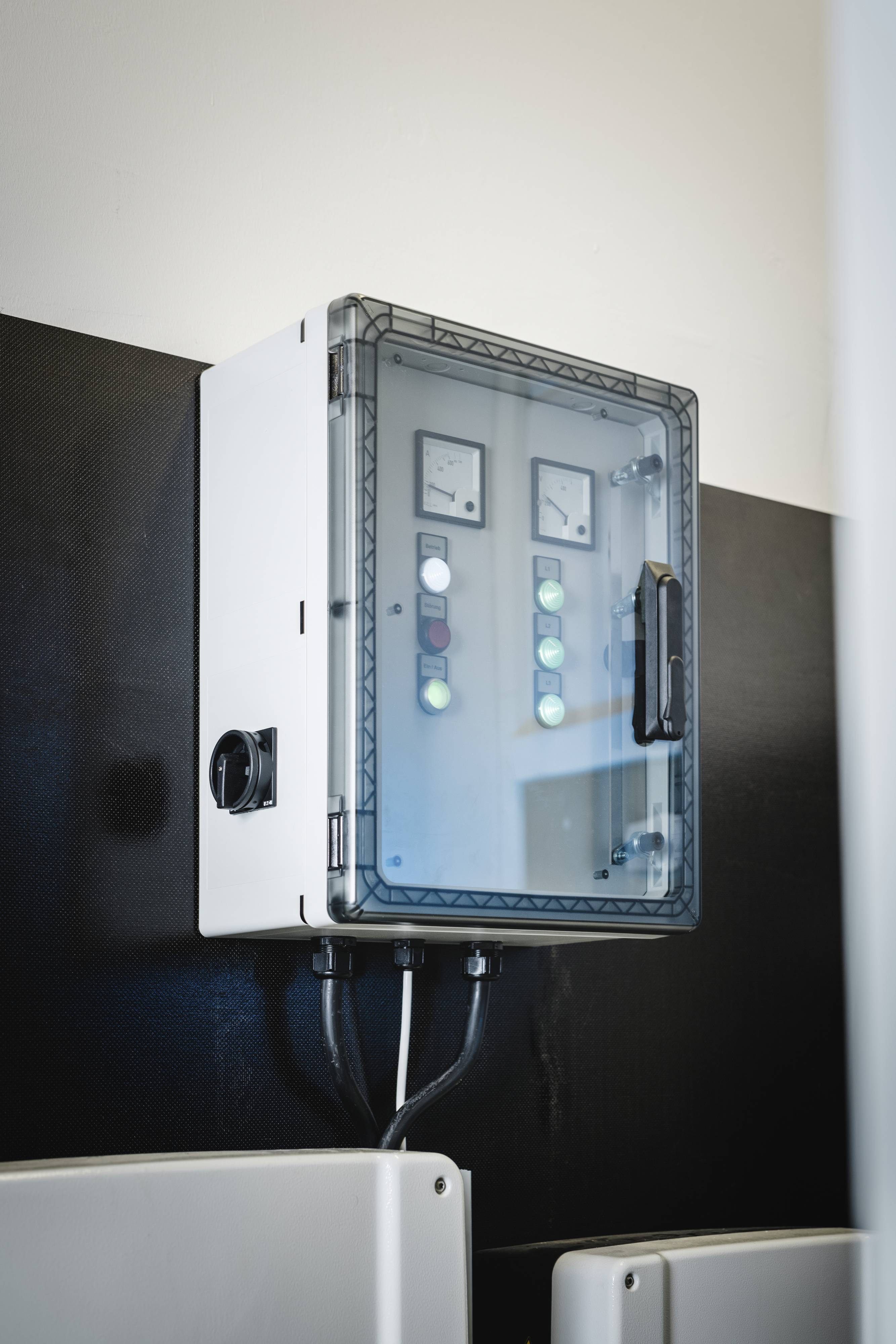 Elektrická rozvodná skříň upevněná na stěně, vybavená několika spínači a indikátory zobrazujícími provozní stav.