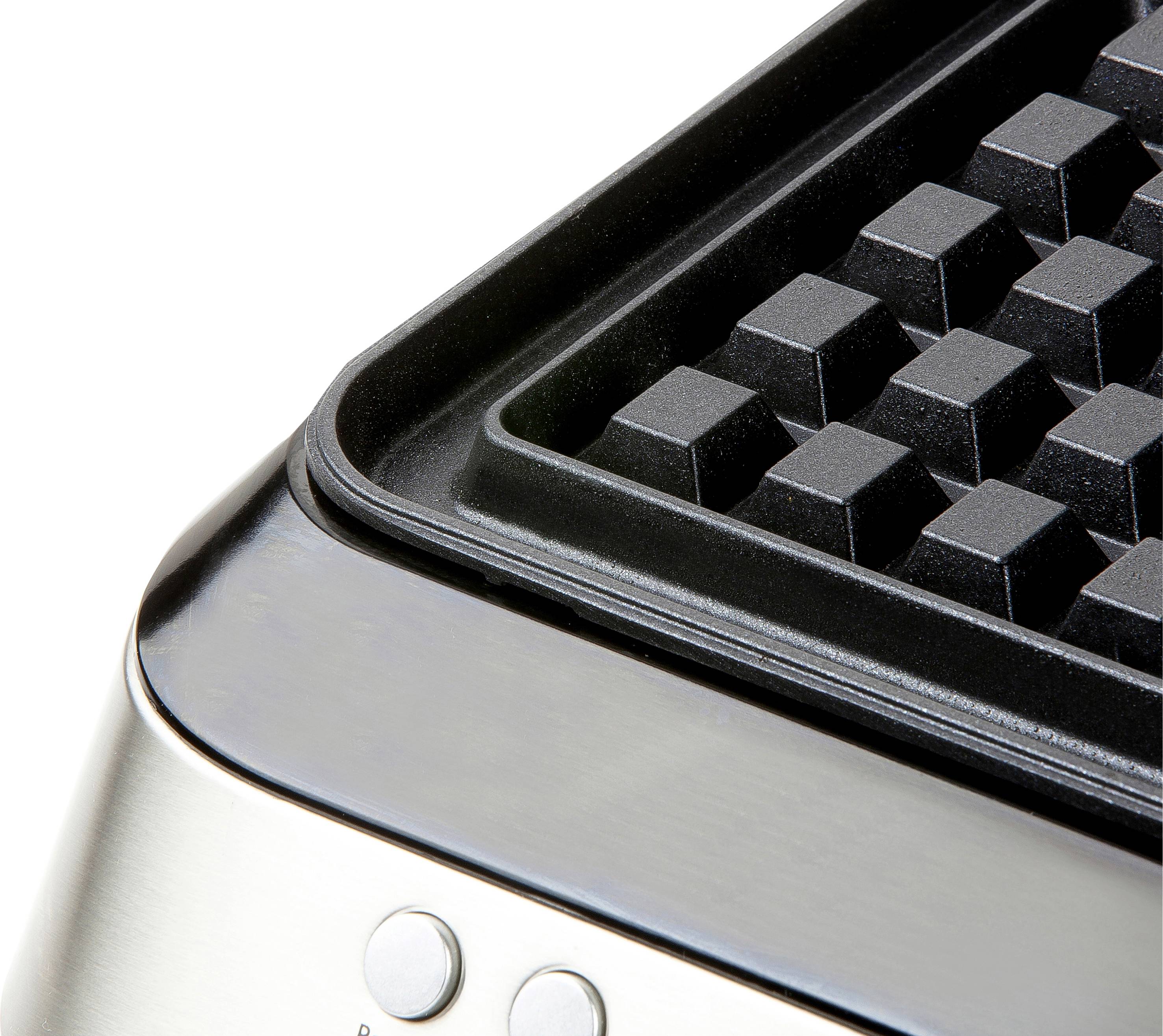 Detailní záběr na vaflovač s mřížkovým vzorem, vpředu jsou viditelné dva kulaté knoflíky.