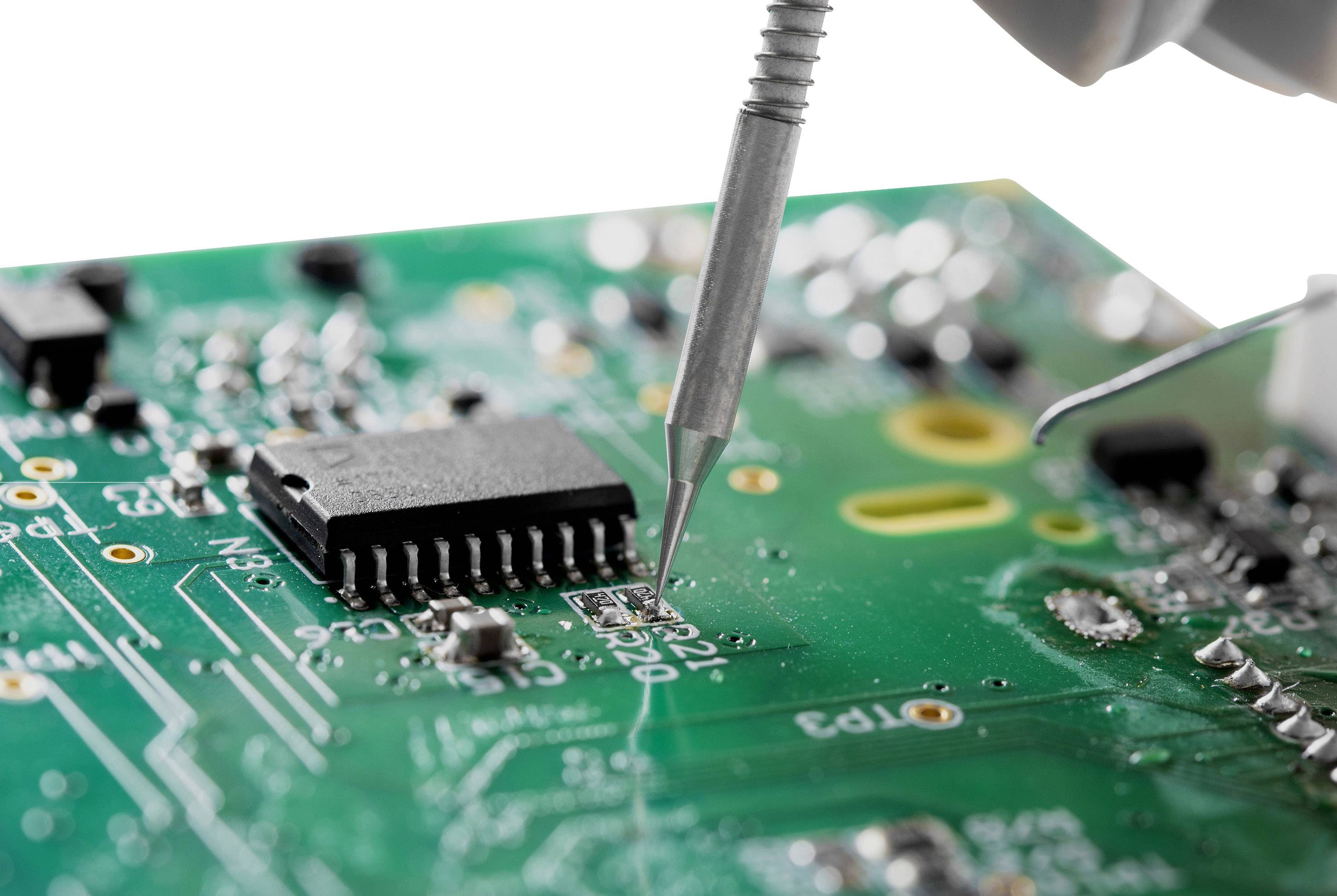 Detailní záběr zelené desky plošného spoje, kde pájecí pero pracuje na elektronické součástce.