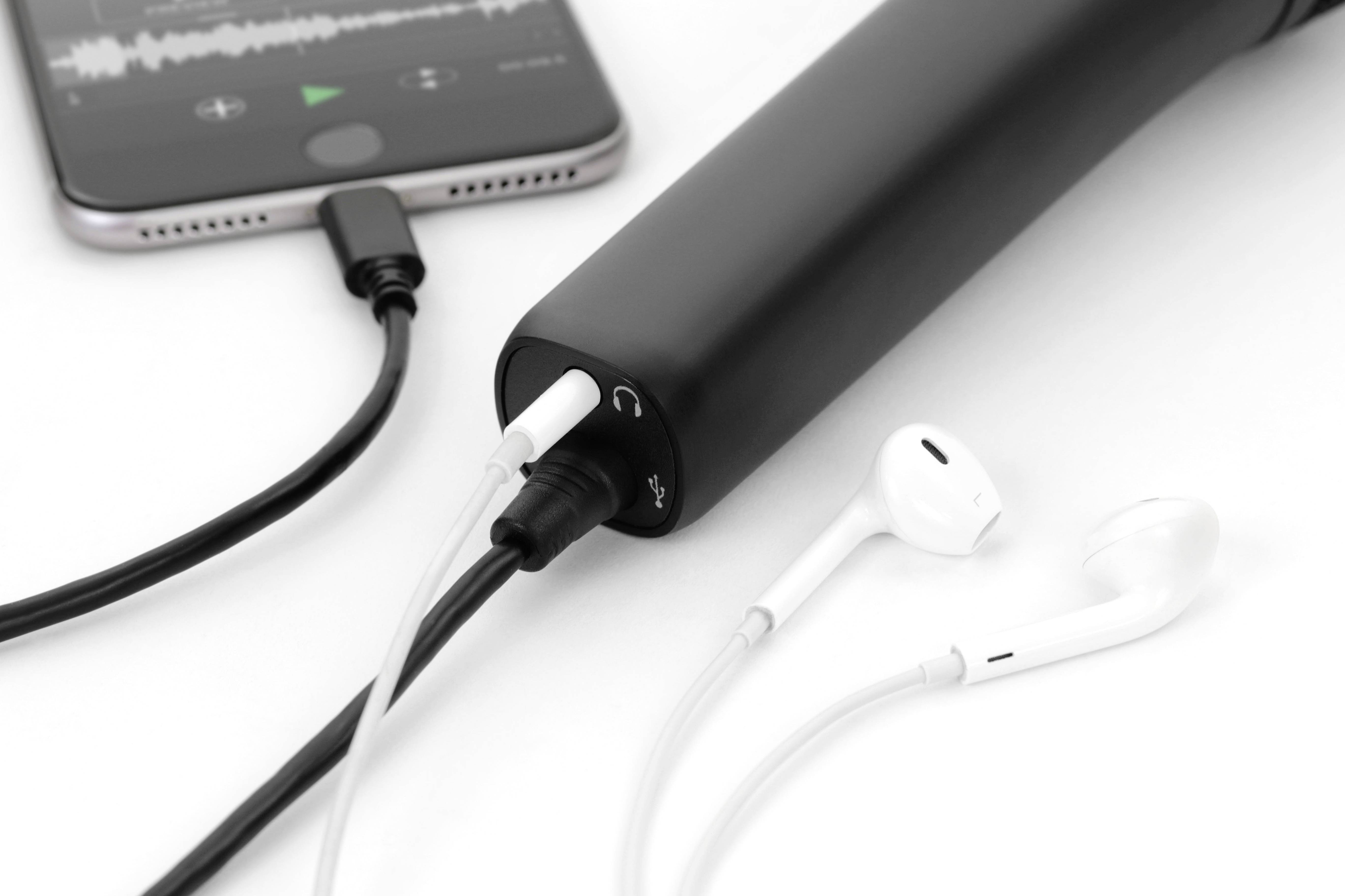 Smartphone, powerbanka a sluchátka jsou propojeny kabely. Na displeji je zobrazena audiosoubor přehrávající se.