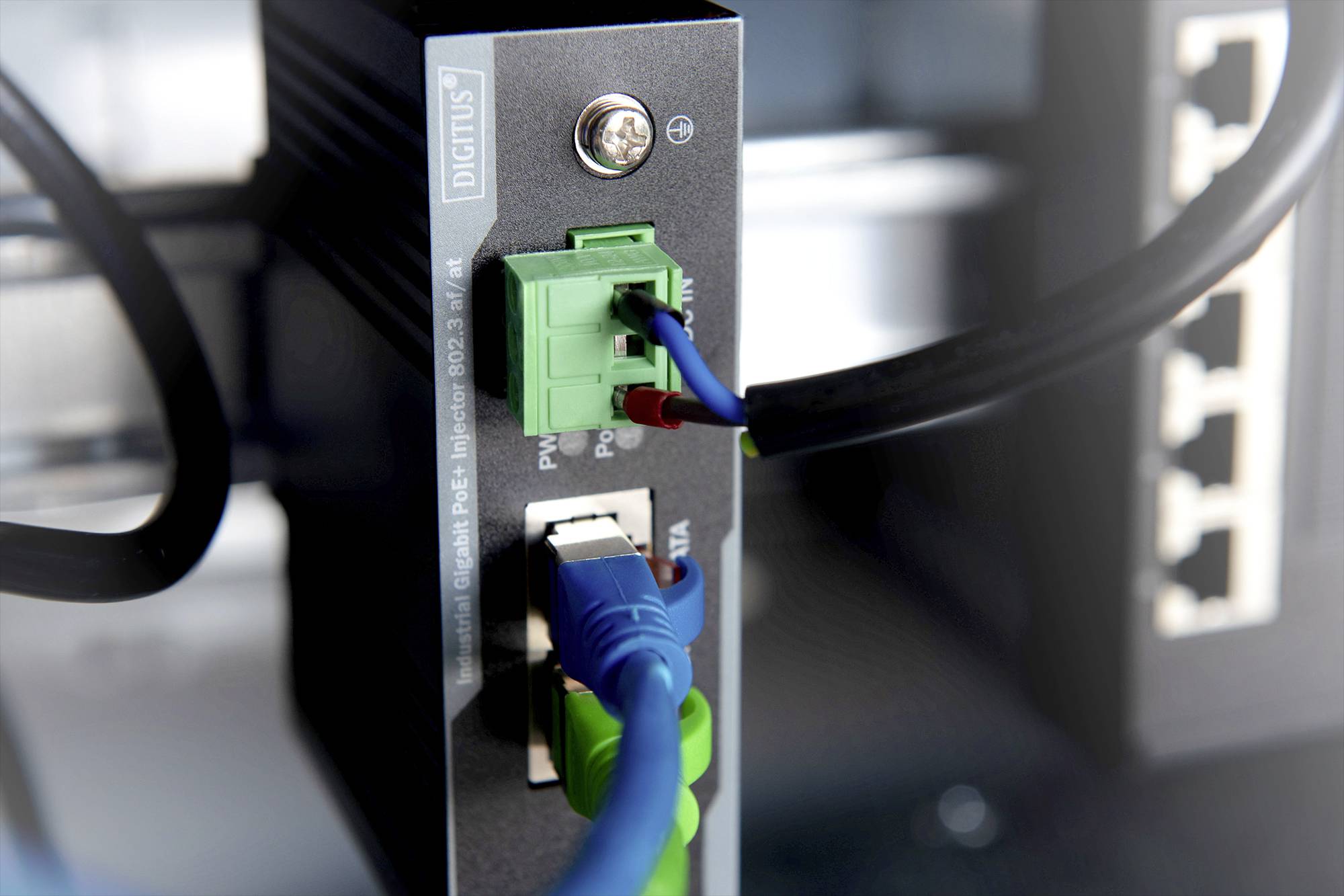 Síťové zařízení s několika kabely připojenými k ethernetovým portům, se zaměřením na zelené a modré kabelové připojení.