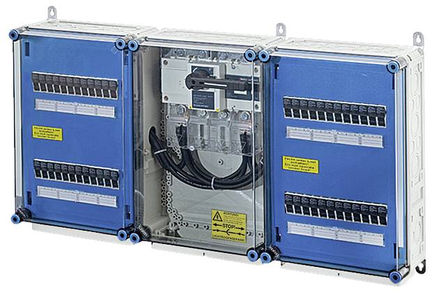 Elektrická rozvodná skříň s otevřenými modrými dvířky odhaluje vnitřní elektrické obvody a kabelové spoje. Výstražná bezpečnostní značka je viditelná.