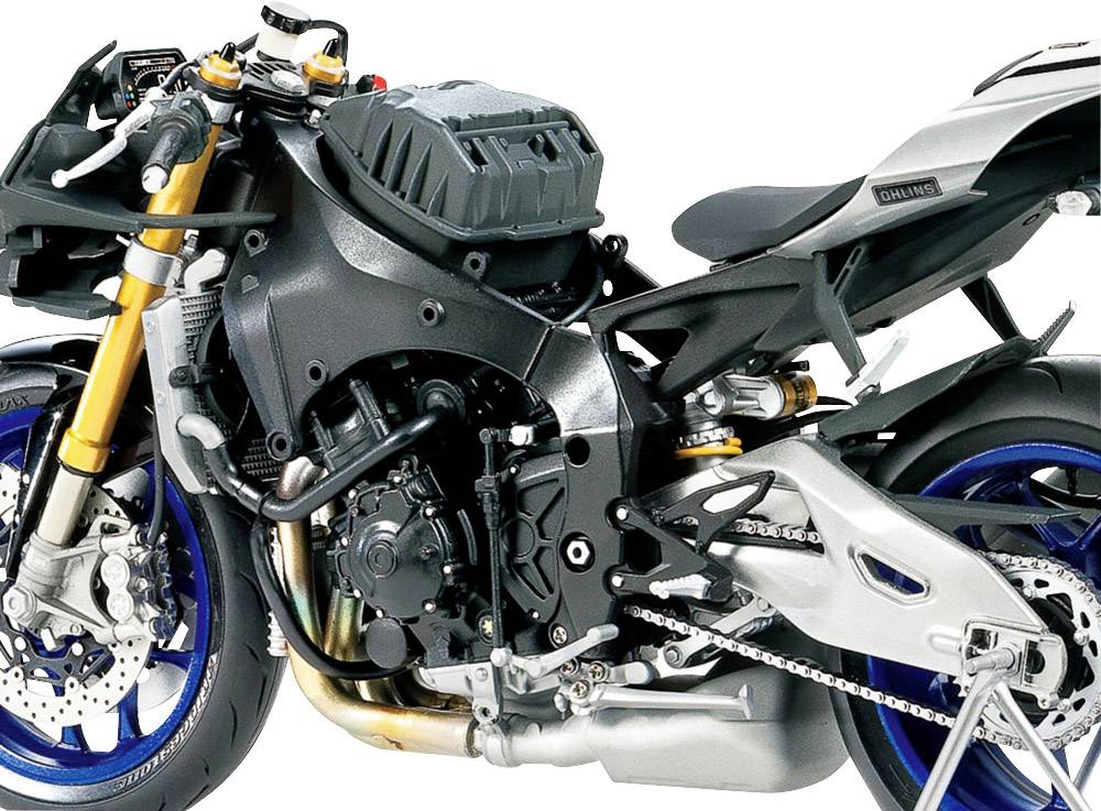 Detail motocyklového motoru se zlatými předními vidlicemi, černými a stříbrnými detaily. Motor je zde zobrazen ve výrazné detailní perspektivě.