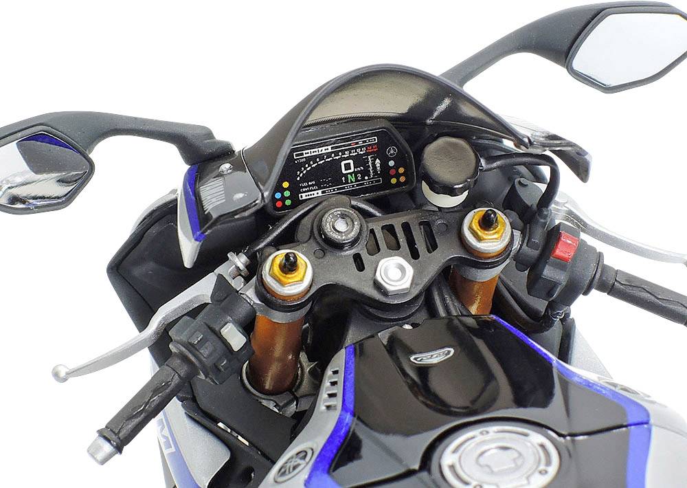 Motocyklový kokpit zobrazuje tachometr s digitálním displejem a ovládacími prvky. Řídítka jsou viditelná vlevo i vpravo.