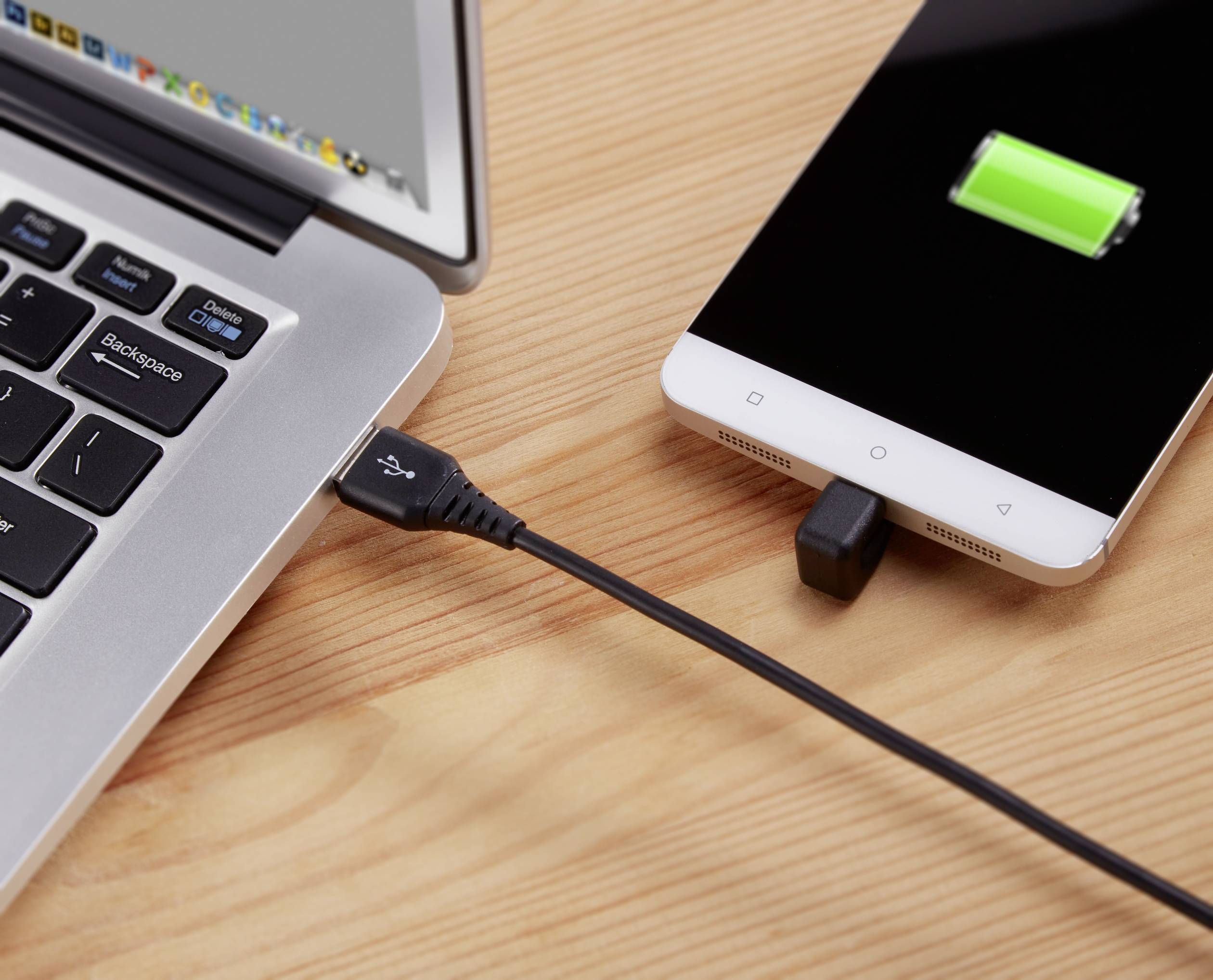 Smartphone je připojeno k laptopu pomocí USB kabelu a nabíjeno. Na displeji telefonu je zobrazován zelený symbol nabíjení.