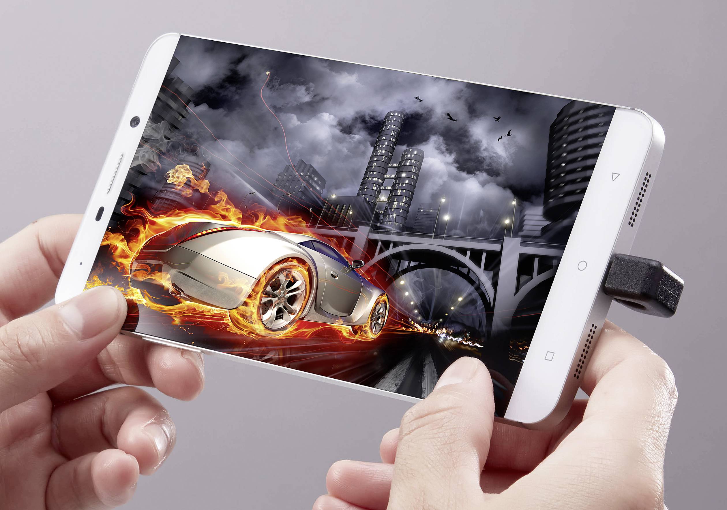 Osoba drží smartphone, který zobrazuje virtuální závodní auto. Auto je obklopeno plameny a jede noční městskou krajinou.