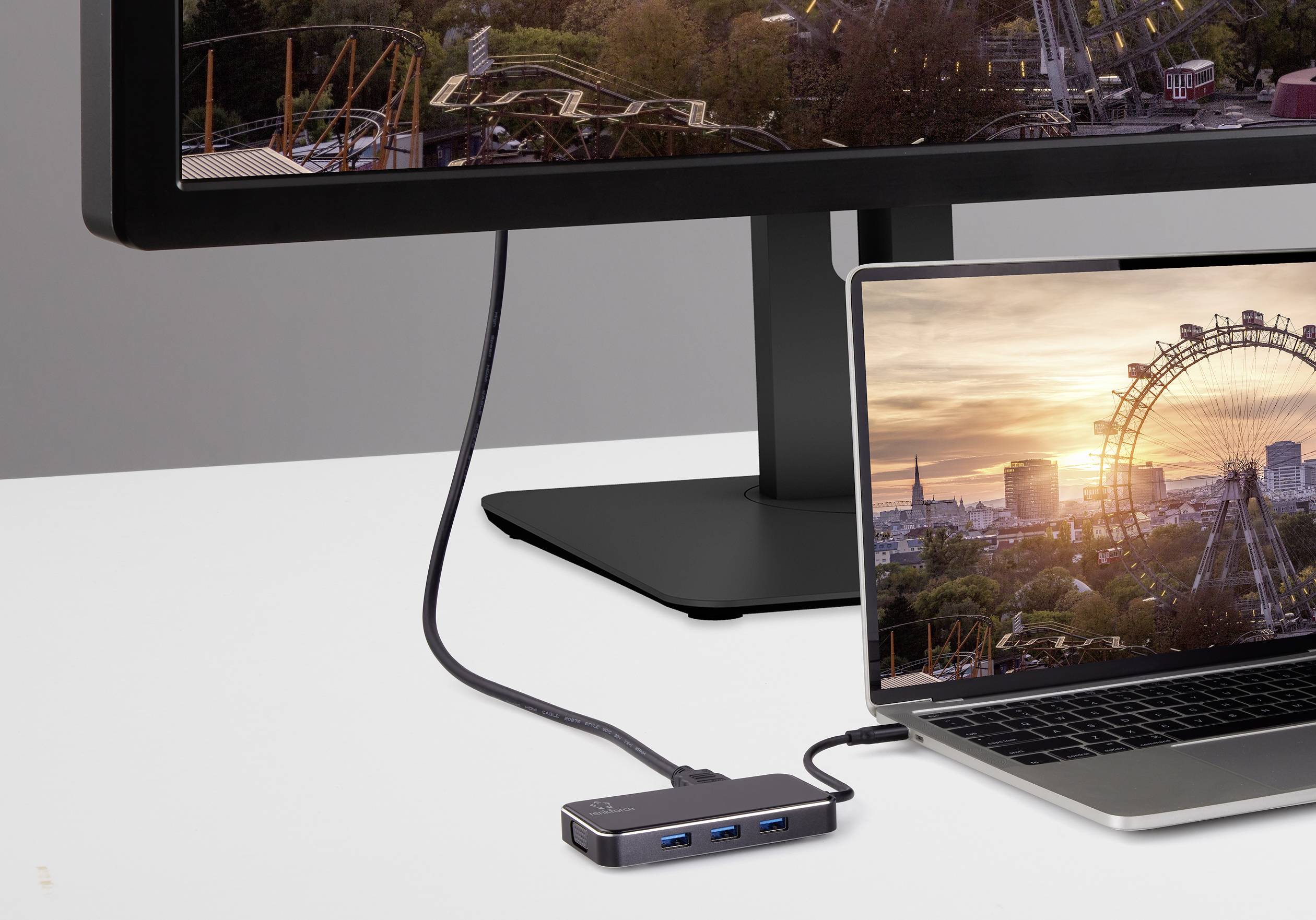 Notebook je připojený k externímu monitoru. Na obou obrazovkách je vidět obrázek obřího kola při západu slunce.