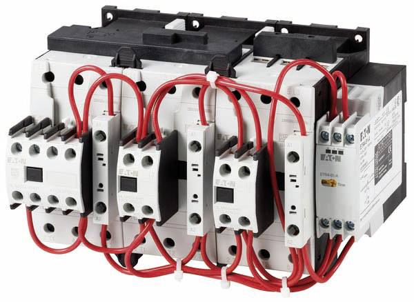 Elektromechanické zařízení s moduly stykačů a červenými kabely, které se používá v elektrických řídicích systémech.