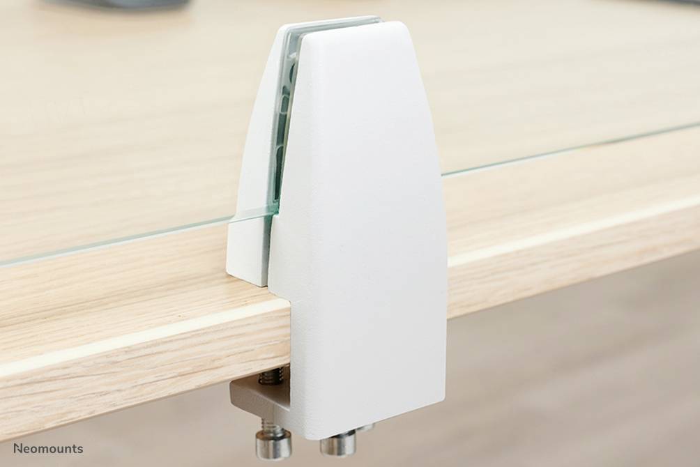 Bílá svorka upevňuje skleněnou desku na okraji dřevěného stolu.