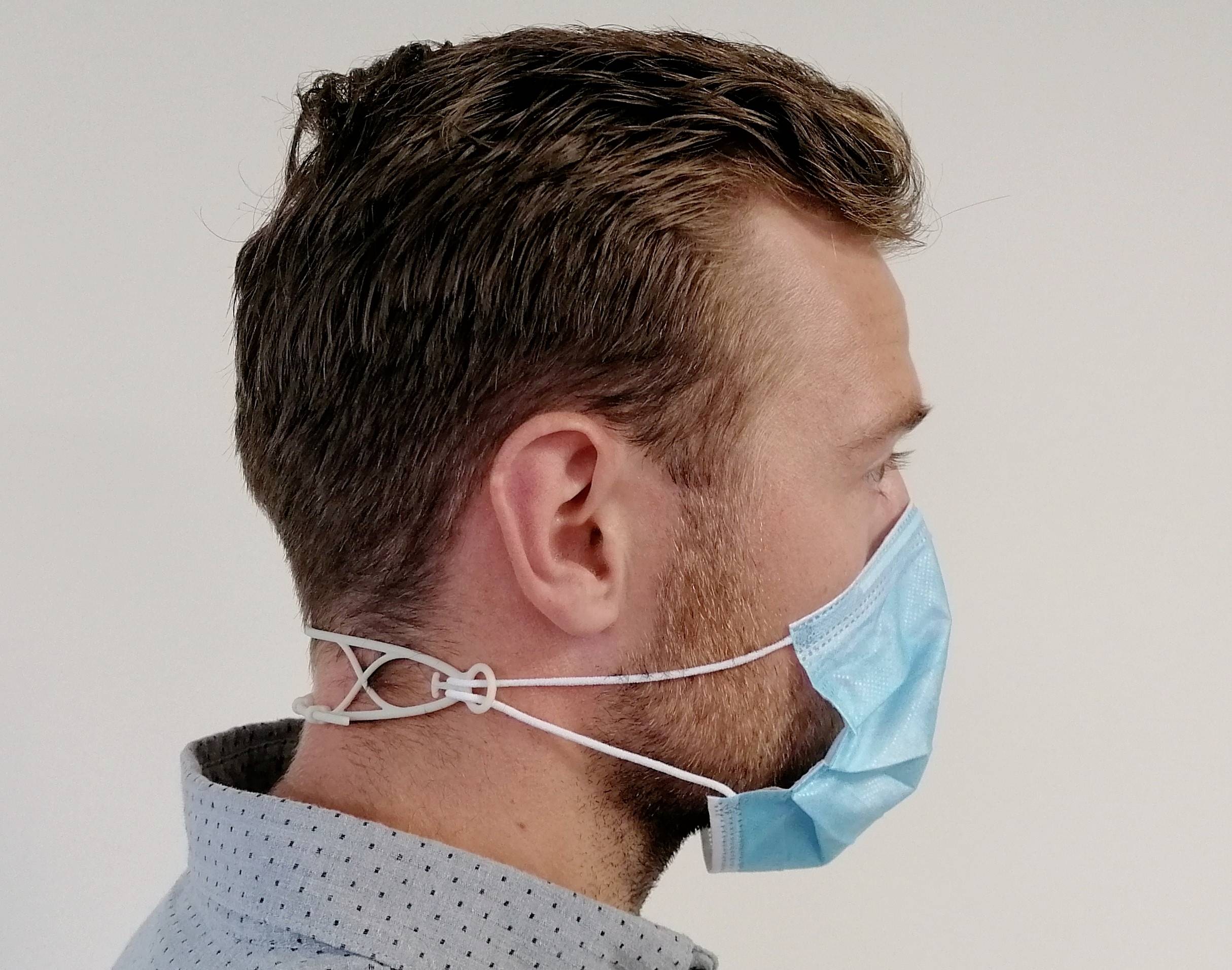 Muž se světlými vlasy nosí modrou obličejovou masku. Maska je upevněná bílými pásky, které jsou uvázané kolem hlavy.
