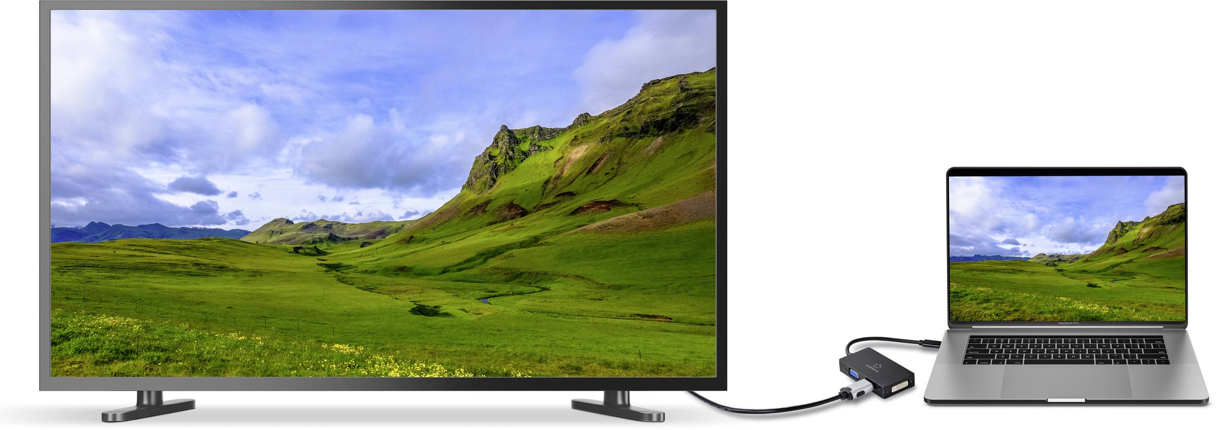Laptop je připojen kabelem k většímu monitoru. Oba displeje zobrazují zelenou krajinu s horami.