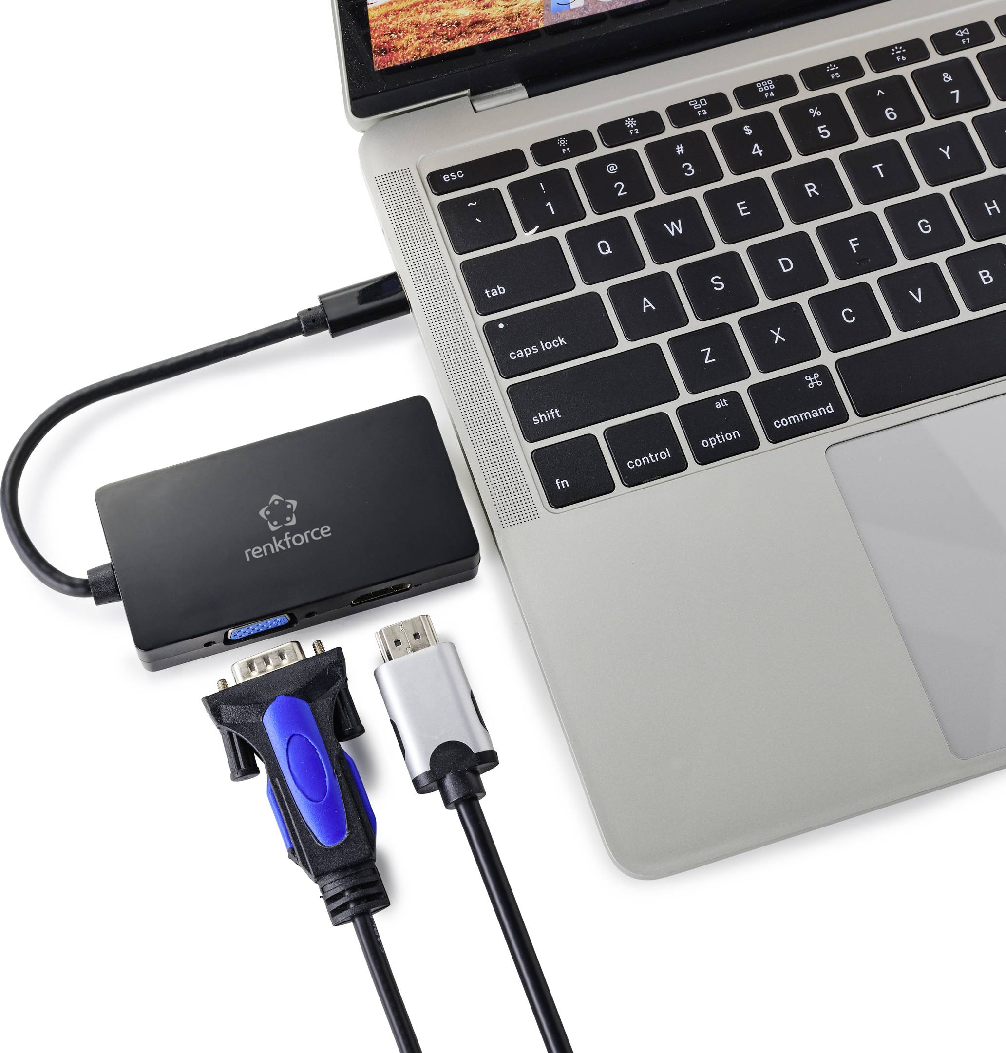 Notebook s připojeným adaptérem, který je prostřednictvím několika kabelů propojen s různými zařízeními, jako jsou HDMI a VGA.