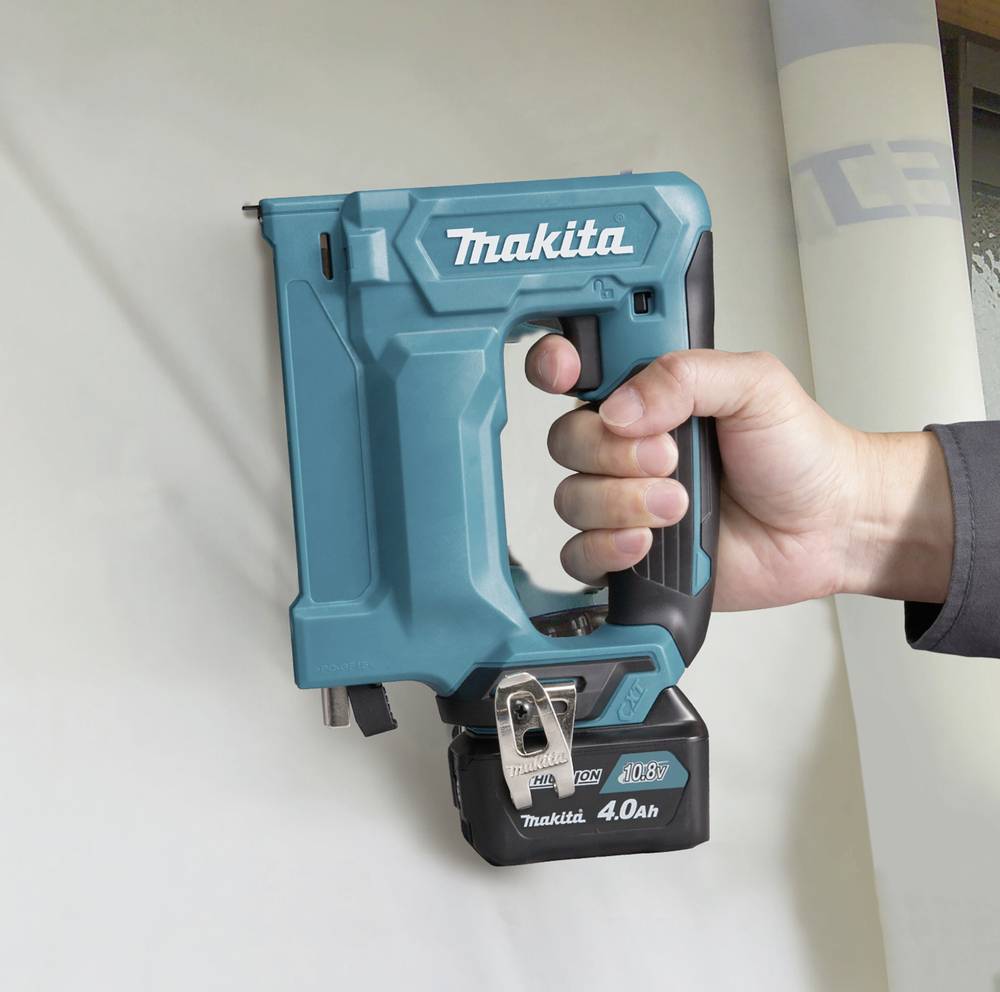 Osoba drží bezdrátový modrý sponkovací přístroj značky Makita, který se používá k upevňování materiálů.