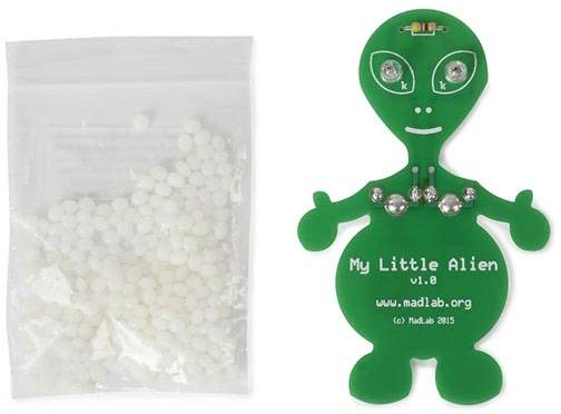 Zelená deska cizince s nápisem 'My Little Alien v1.0' vedle sáčku s malými bílými díly.