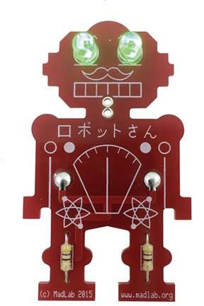Červená robotická deska plošných spojů s osvětlenými LED diodami místo očí. Japonský text na hrudi, dva symboly ve tvaru atomu dole.