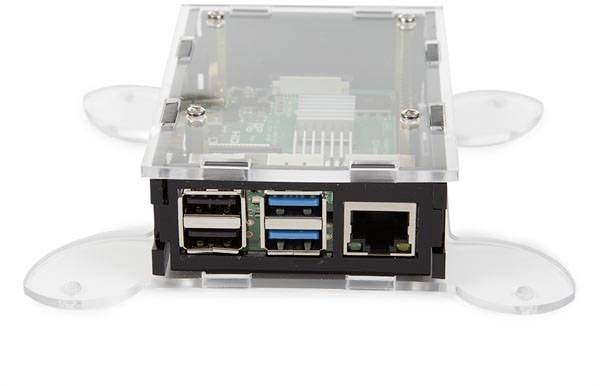 Průhledné pouzdro s deskou počítače, zobrazující několik USB portů a ethernetový port vpředu, stojící na nožkách.