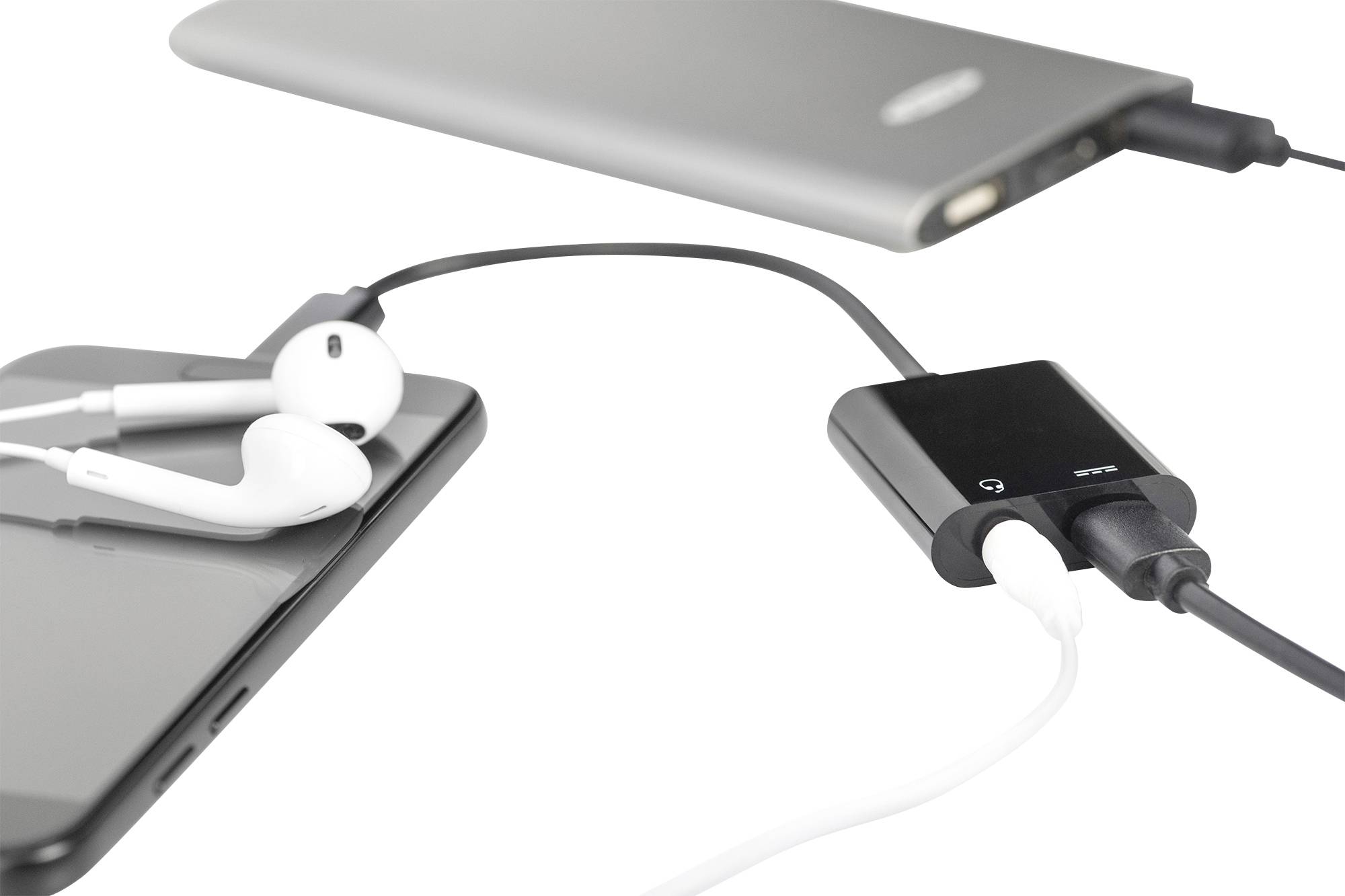 Smartphone s připojenými bílými sluchátky a černým USB hubem, který je připojen dvěma kabely k šedé powerbance.
