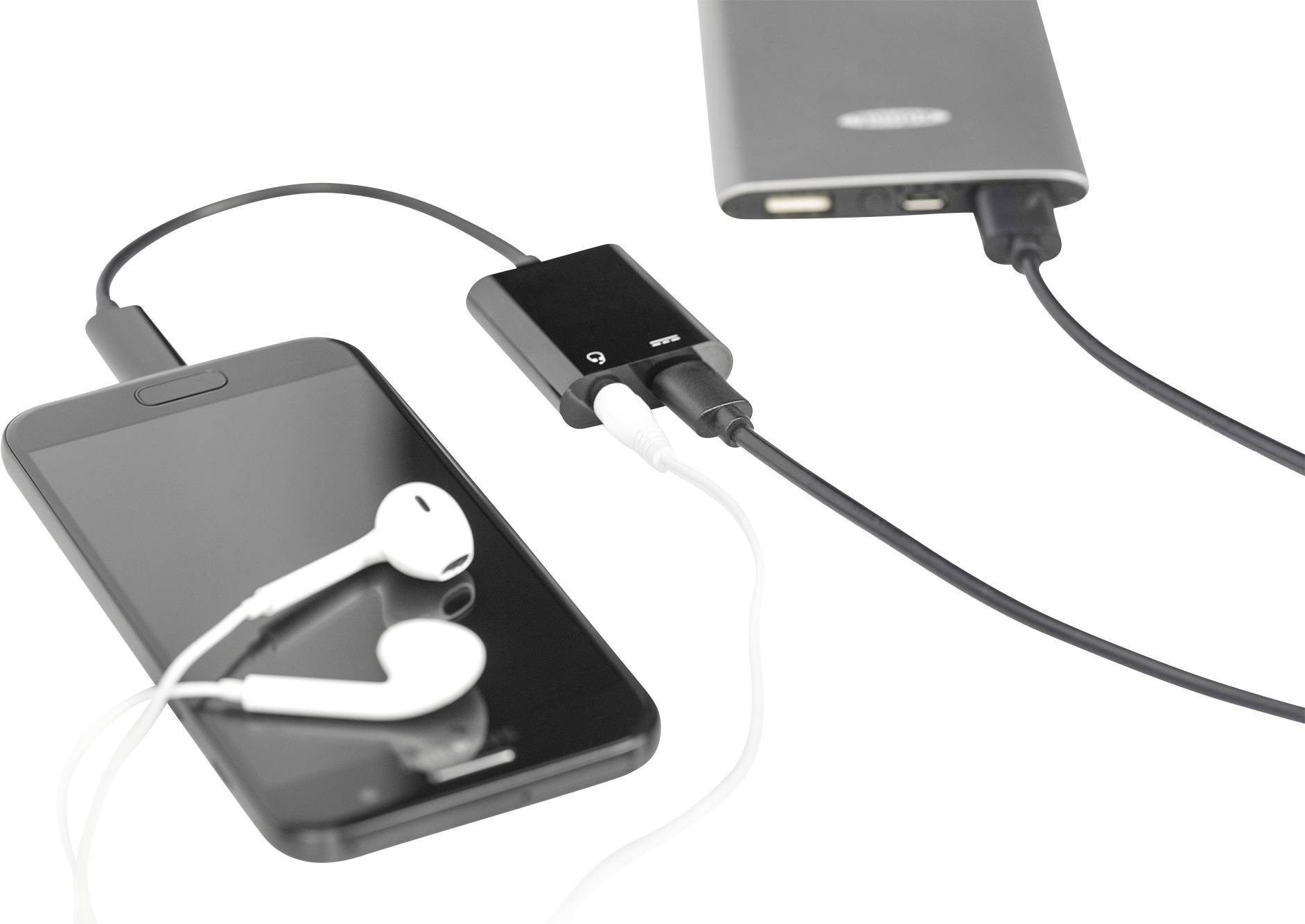 Smartphone se zapojenými bílými sluchátky, připojené k přenosnému powerbance přes USB kabel; znázorňuje mobilní nabíjení.