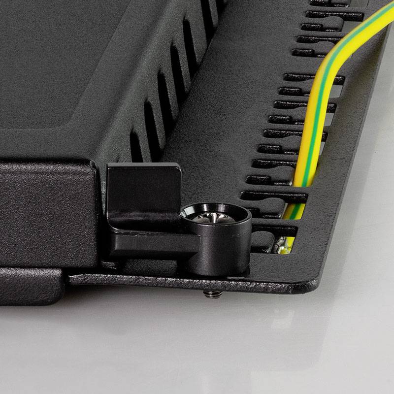Detailní záběr průmyslového zařízení s černým krytem a pevnou konzolí; jsou viditelné žluté a zelené kabely.