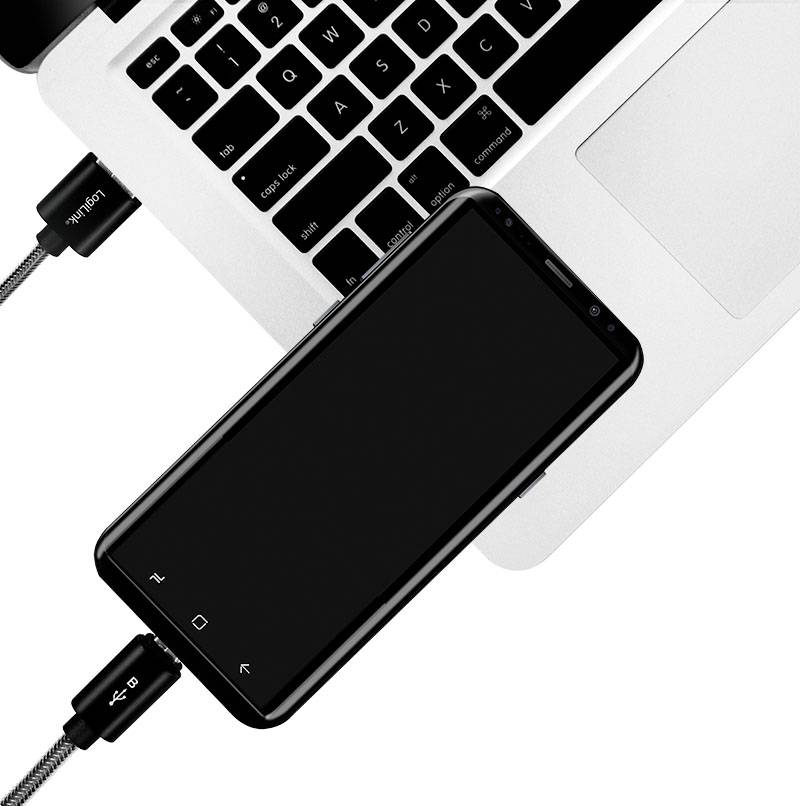Smartphone je připojeno k laptopu přes USB kabel. Laptop je částečně viditelný a smartphone je vypnutý.