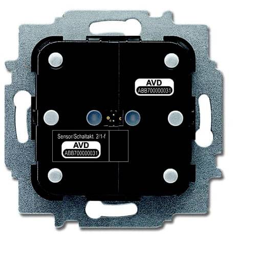 Elektronické spínací zařízení ve čtvercovém tvaru s bočními upevňovacími otvory, označené štítkem "Senzor/Spínací akt 2/1-f".