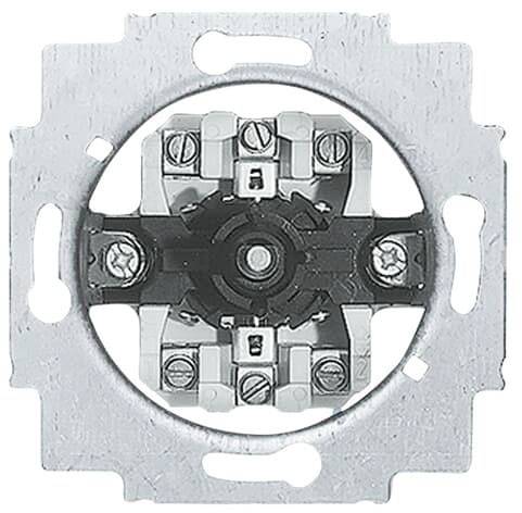 Kulatý kovový vypínač bez krytu, s viditelnými šrouby a kontakty, namontovaný v čtvercové základně.