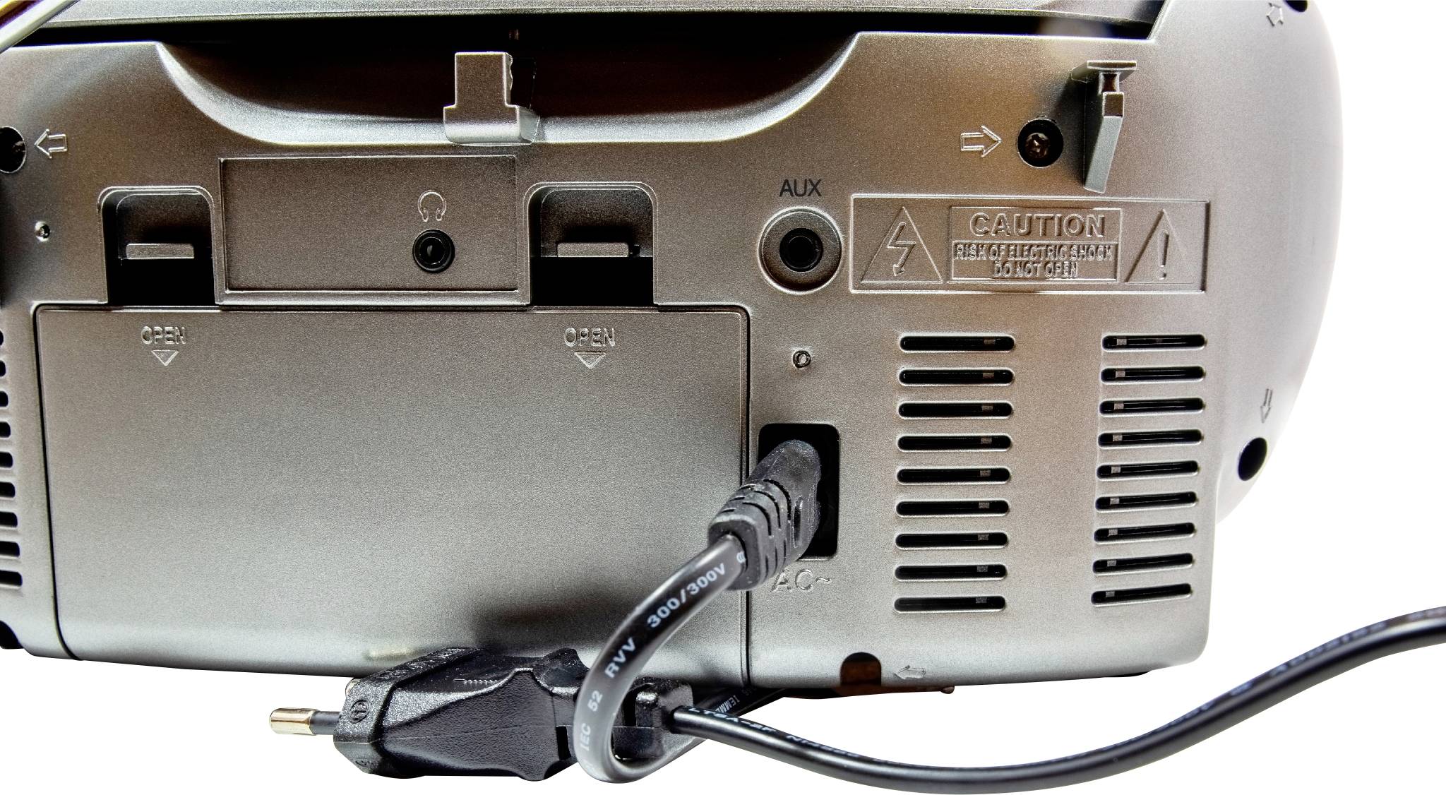 Spodní strana elektronického zařízení s několika porty, včetně AUX vstupu a připojeného napájecího kabelu.