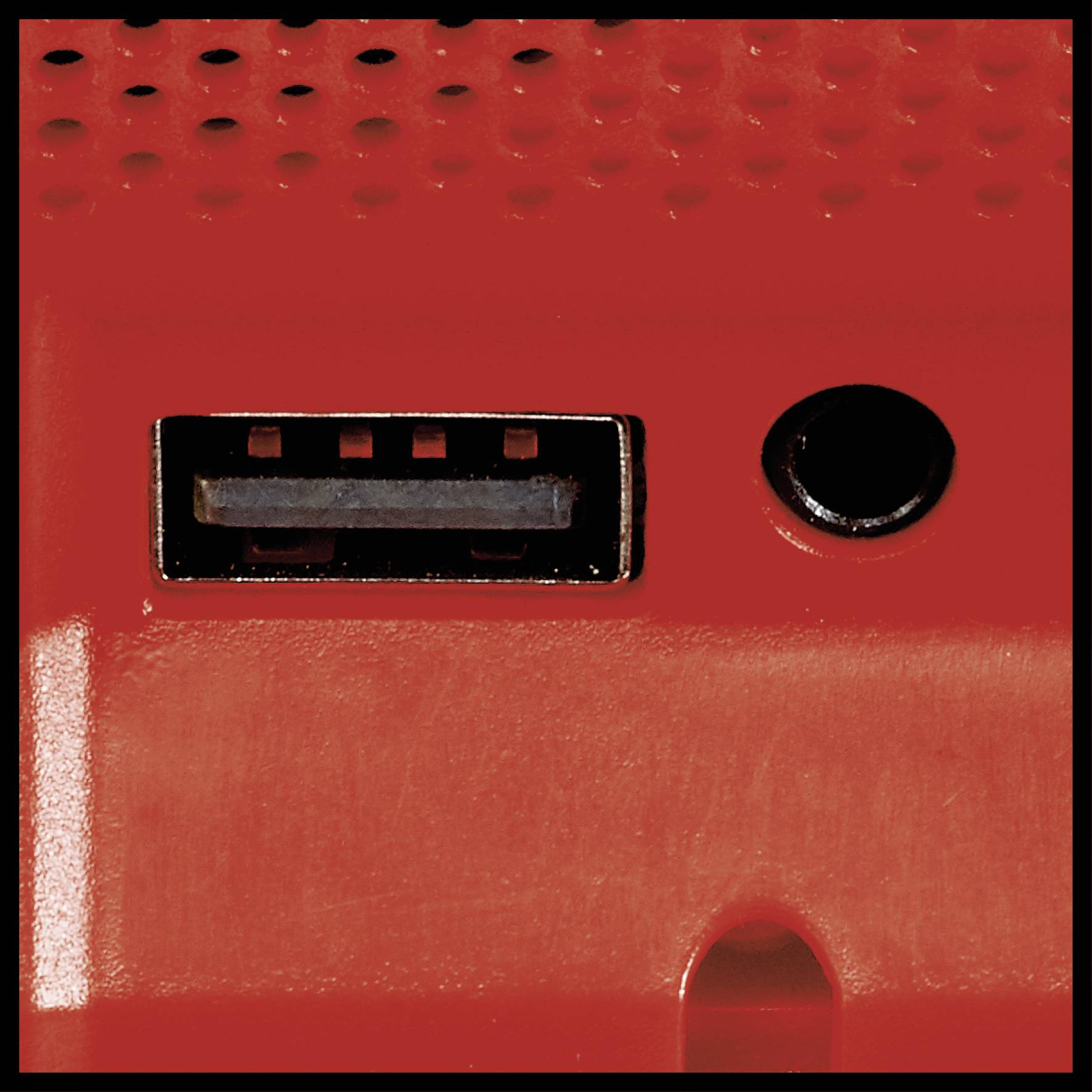 Detailní záběr červeného zařízení s USB portem a kulatým audio konektorem.
