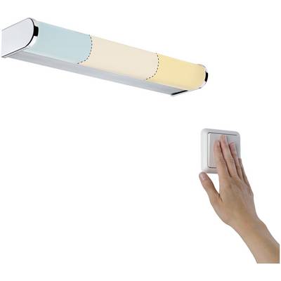 Ruka zapíná moderní, štíhlou nástěnnou lampu. Lampa svítí pastelově modrými, béžovými a žlutými tóny.