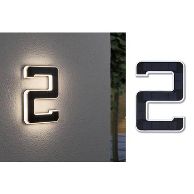 Osvětlené domovní číslo '2' na zdi, vpravo vedle stejné číslo jako tmavá cedule na bílém pozadí.