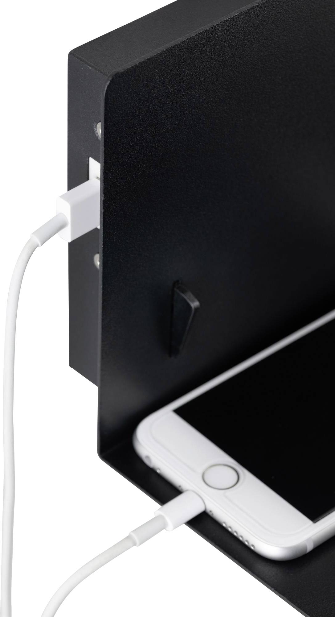 Mobilní telefon se nabíjí na polici. Je připojen pomocí USB kabelu zapojeného do bočního portu.