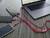 Laptop nabíjí tři smartphony pomocí červených USB kabelů na tmavém dřevěném stole.
