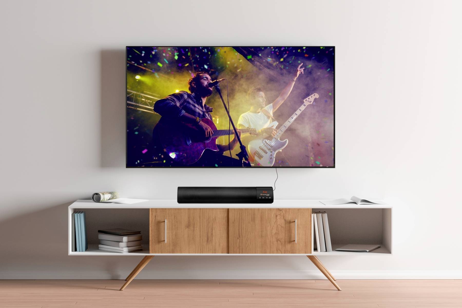 Obrázek zobrazuje moderní konzoli v obývacím pokoji s plochým televizorem. Na obrazovce je vidět živé hudební vystoupení.