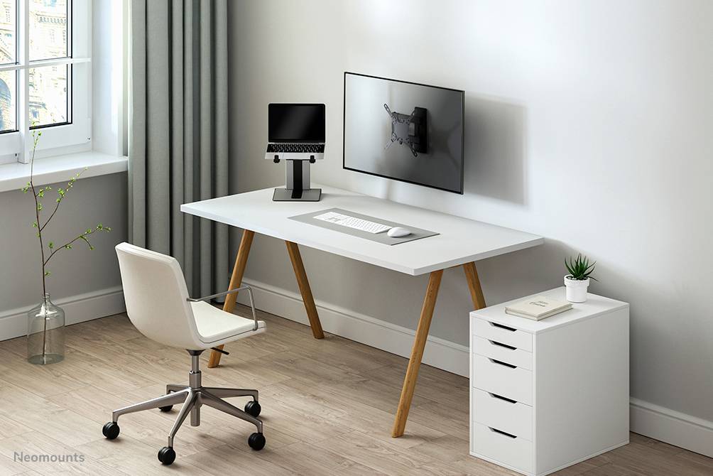 Moderní pracoviště s bílým stolem, držákem monitoru s obrazovkou, klávesnicí a bílou židlí na dřevěné podlaze.