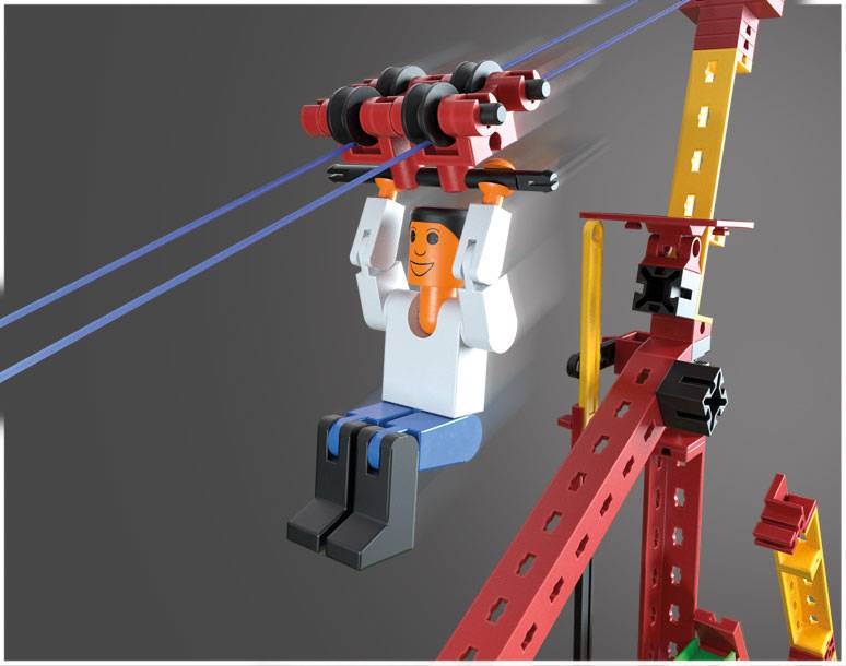 Modelářská sada zobrazuje postavu na lanové dráze, obklopenou pruhovanými červenými a žlutými strukturami v pozadí.