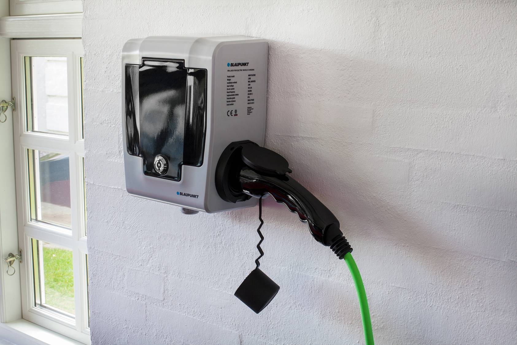 Nástěnná nabíjecí stanice s připojeným nabíjecím kabelem, připravená k nabití elektromobilu.